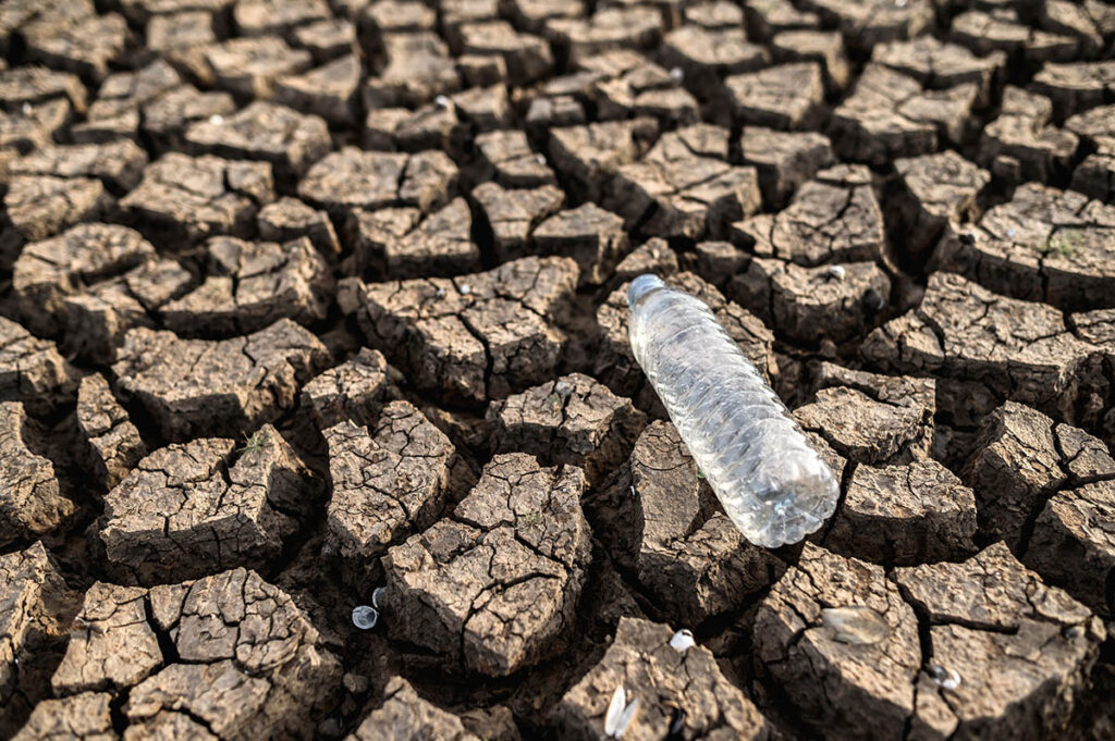 Crisis del agua, botella vacía sobre suelo seco